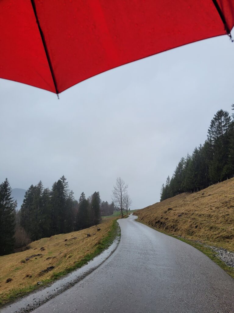 Wandernde mit Regenschirm bei einer Tour durch das Oybachtal.